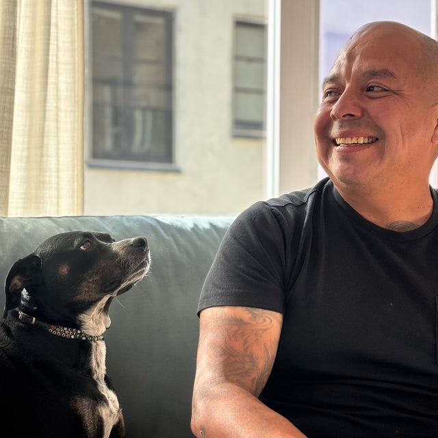 Oscar laughing on the couch while his dog looks up at him